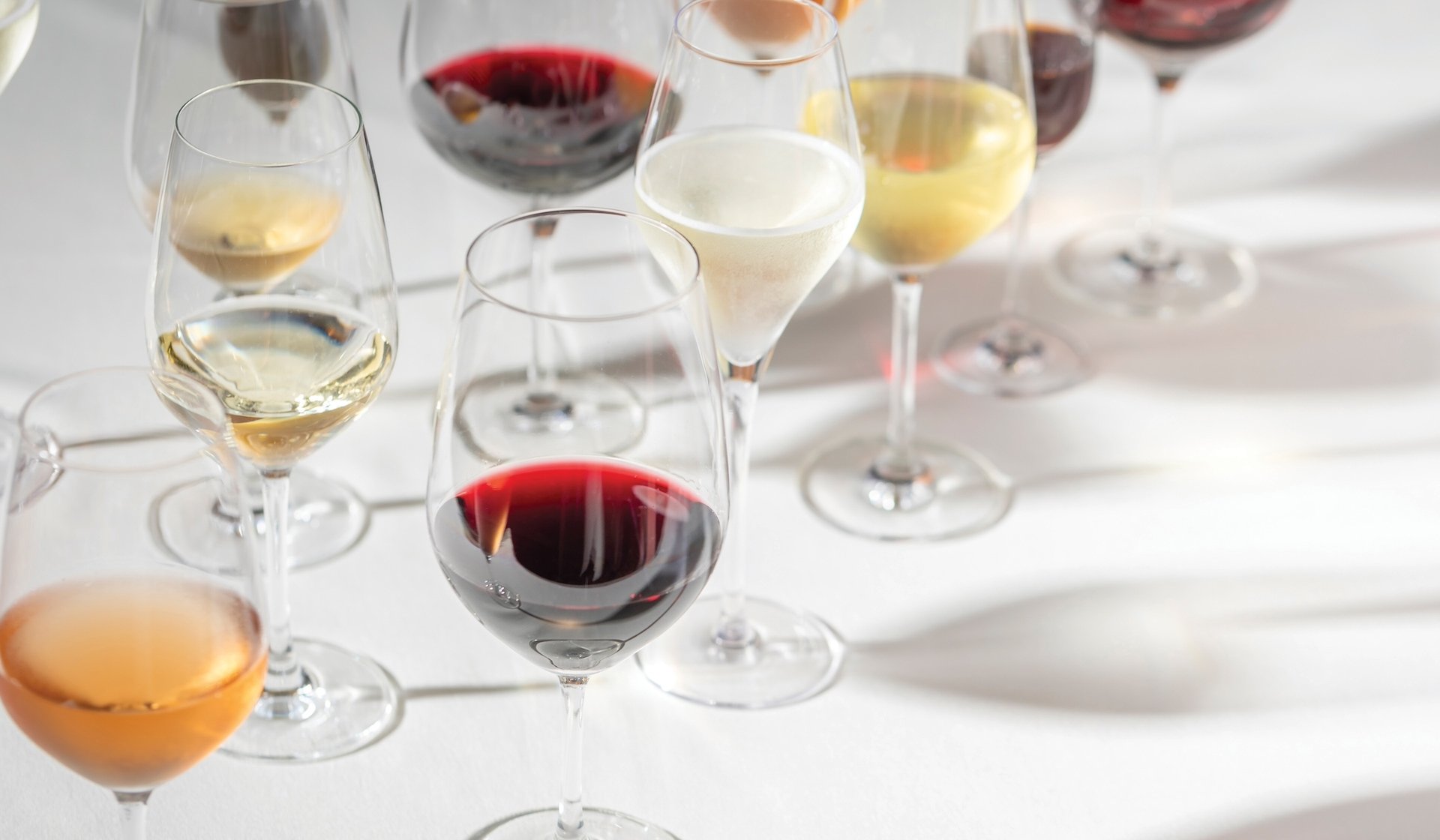 A variety of wine glasses filled with wines of many colors