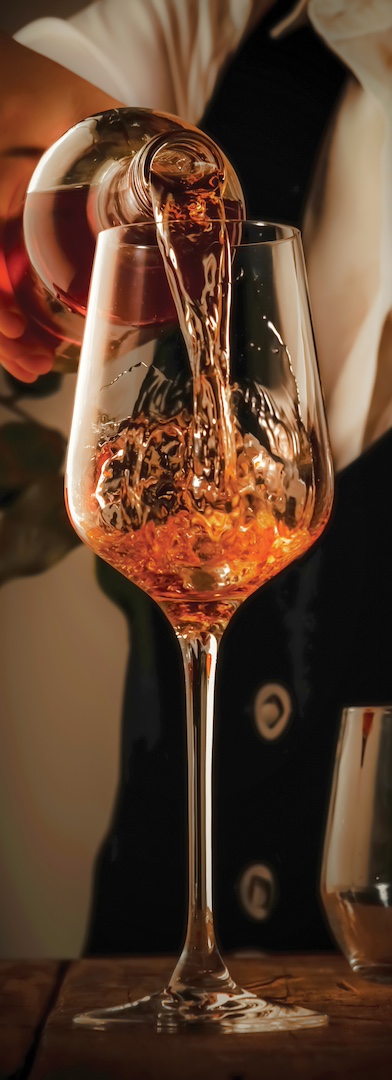 A hand pouring an orange wine into a glass