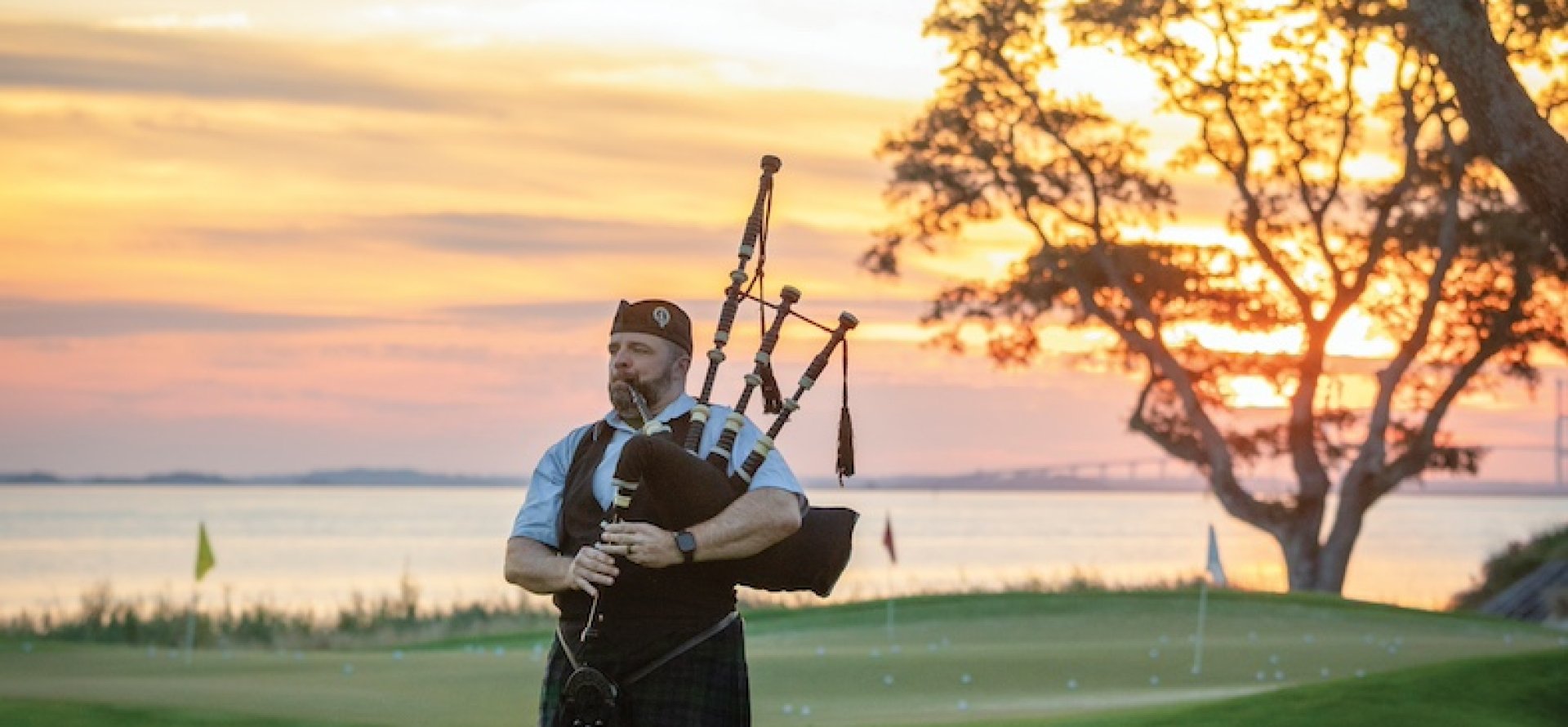 A bagpiper plays on a golf green at dawn