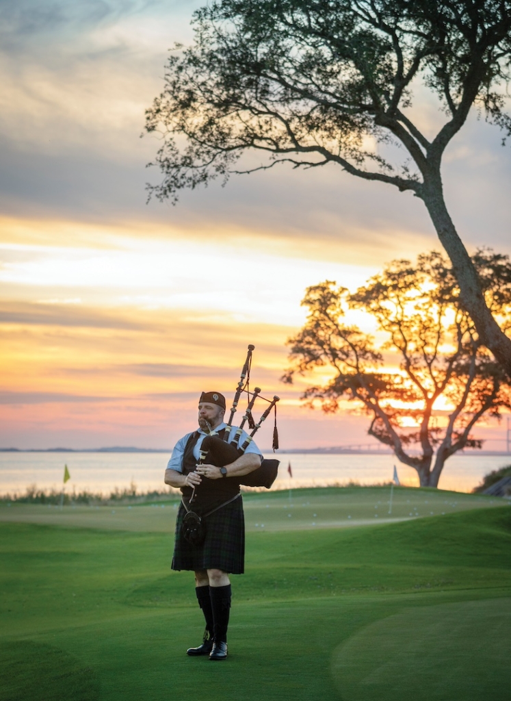 A bagpiper plays on a golf green at dawn