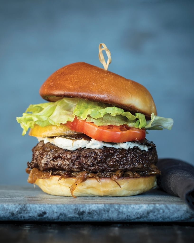 A hamburger with lettuce and tomato, held together with a toothpick