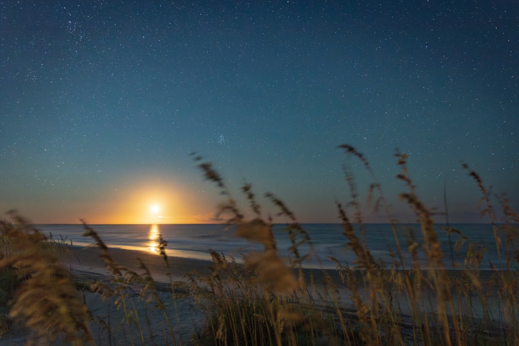 The view from a beach of the sun setting over the ocean