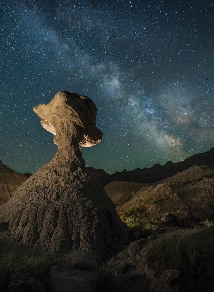 A lone rock structure rises against the night sky in Badlands National Park.